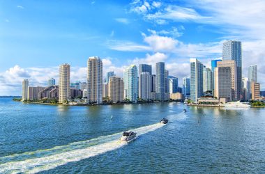 aerial-view-miami-skyscrapers-with-blue-cloudy-sky-white-boat-sailing-miami-downtown-min